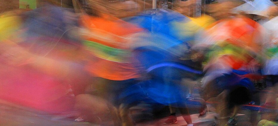 Runners in motion at the start of a half marathon, seen as a colorful blur