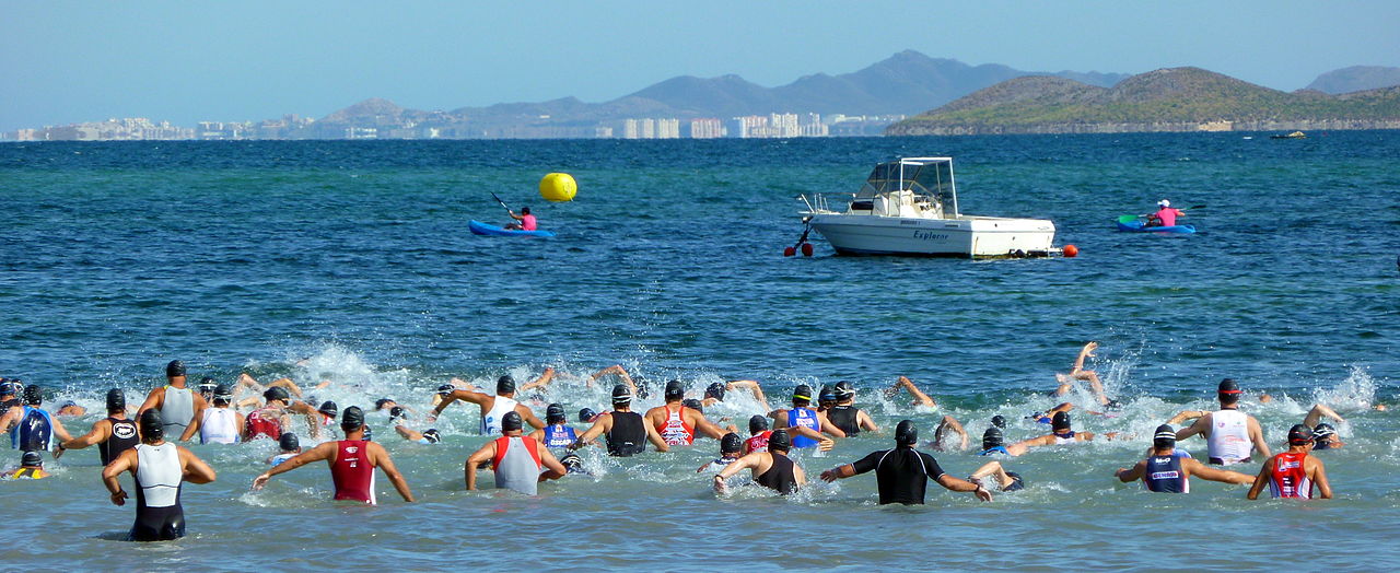 Triathletes wading into the sea at the start of a triathlon swim